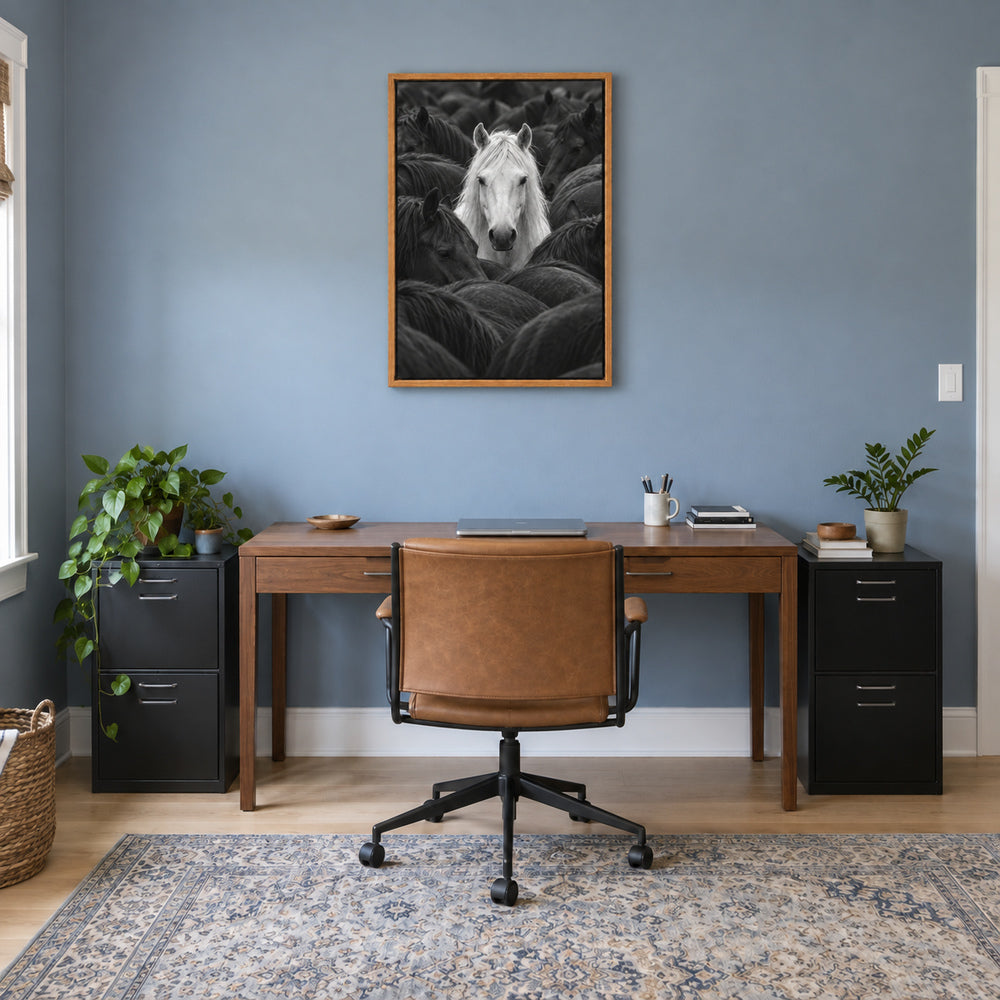 white horse centered in a dark herd black-and-white photograph in brown frame room scene
